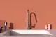 Küchenarmatur von Ideal Standard mit einem modernen Design, montiert über einem rechteckigen Spülbecken, vor einer peachfarbenen Wand.